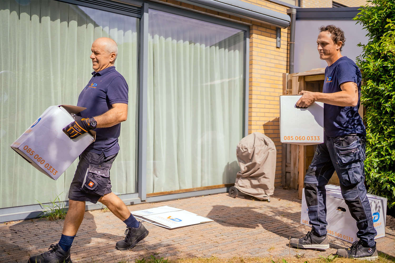 Twee verhuizers van Verhuisbedrijf Draagkracht dragen dozen naar binnen